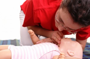 Lady administering CPR on infant dummy